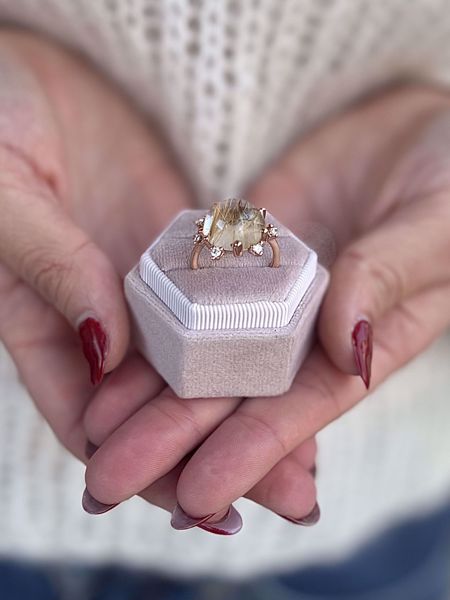 Ring i 585 rosegull med cabochonslipt rutilkvarts, omkranset av 7 diamanter med totalvekt på 0,25 carat. 